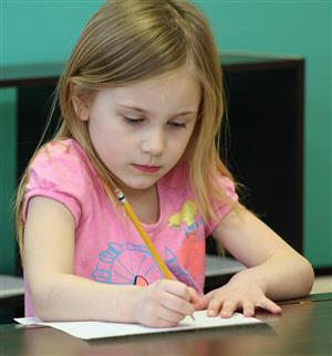 female kindergarten student writing on paper 